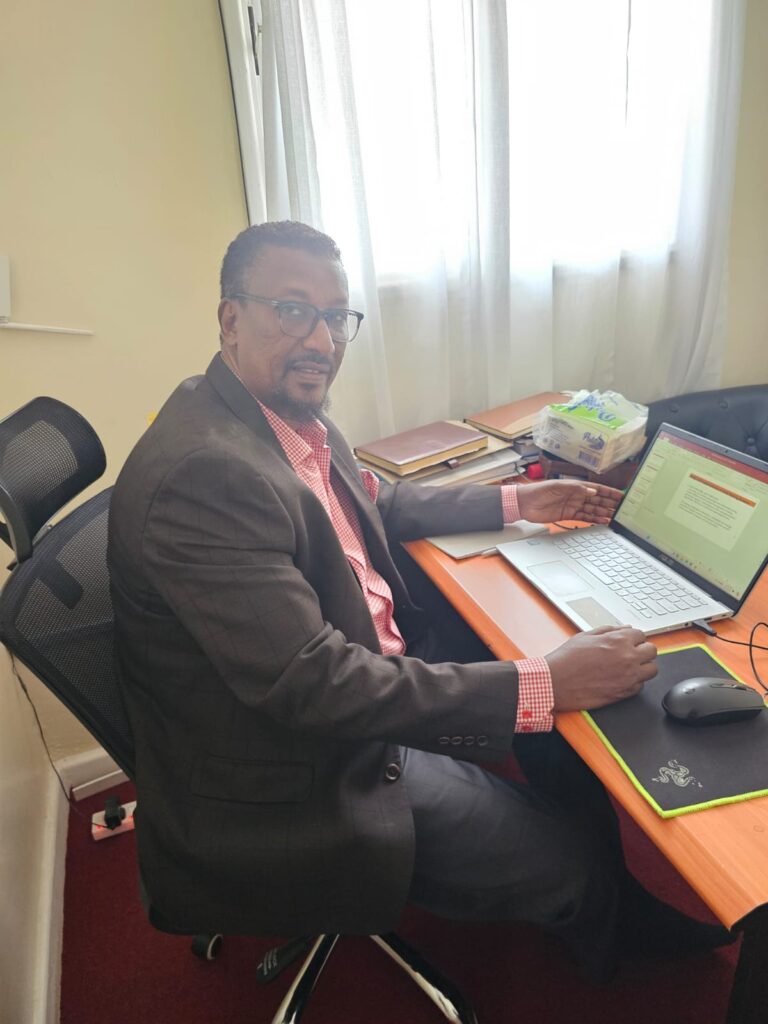 Dr. Mohamed Abdinoor Dahir in a blue plaid suit and tie
