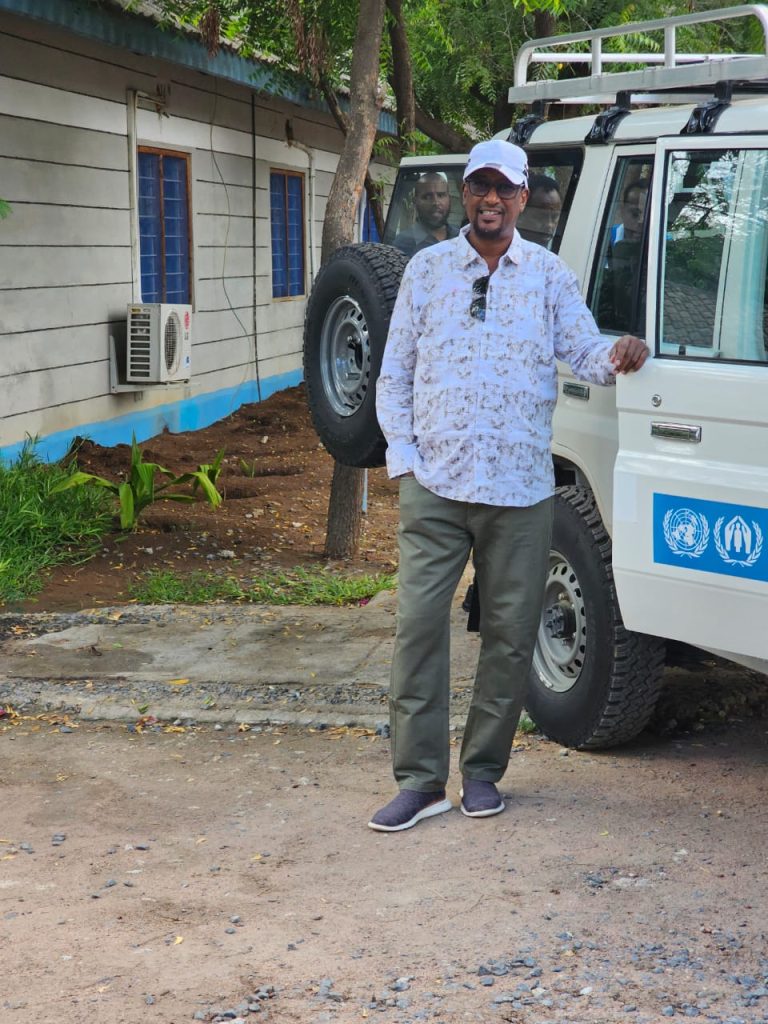 Prof. Mohamed Abdinoor Dahir, Vice-Chancellor of Islamic University of Kenya, standing beside a UNHCR vehicle during his visit to Dadaab refugee camp